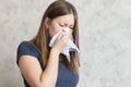 Sick woman with handkerchief sitting at home with flue, virus, cold, seasonal allergy symptom. Young woman blows her nose or