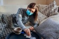 Sick woman having fever coronavirus flu or cold. Girl lying in bed wearing protective mask taking pills and water Royalty Free Stock Photo