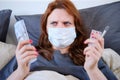 A sick woman in a mask holds dollars and a thermometer in her hands. Money for the treatment of a girl with the flu