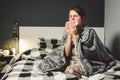 Sick woman with runny nose, sitting in bed. woman feeling unwell and sneeze bedroom. Woman holding tissue ,flu symptoms Royalty Free Stock Photo