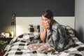 Sick woman with runny nose, sitting in bed. woman feeling unwell and sneeze bedroom. Woman holding tissue ,flu symptoms Royalty Free Stock Photo