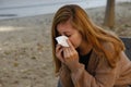 Sick woman sneezing and blowing her nose in a handkerchief tissue, outdoor Royalty Free Stock Photo