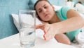 Portrait of sick woman taking glass of water from bedside table Royalty Free Stock Photo