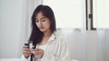 Sick woman taking pills with glass of water in hand while sitting on bed. Royalty Free Stock Photo