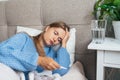 Sick woman with thermometer lying in bed under blanket. Headache, flu, cold, virus. Royalty Free Stock Photo