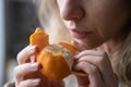 Sick woman trying to sense smell of fresh tangerine orange, has symptoms of Covid-19, corona virus Royalty Free Stock Photo