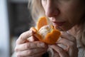 Sick woman trying to sense smell of fresh tangerine orange, has symptoms of Covid-19, corona virus Royalty Free Stock Photo