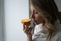 Sick woman trying to sense smell of half fresh orange, has symptom of Covid-19, loss of smell, taste Royalty Free Stock Photo