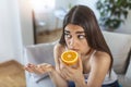 Sick woman trying to sense smell of half fresh orange, has symptoms of Covid-19, corona virus infection - loss of smell and taste Royalty Free Stock Photo