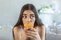 Sick woman trying to sense smell of half fresh orange, has symptoms of Covid-19, corona virus infection - loss of smell and taste Royalty Free Stock Photo