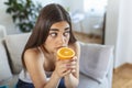 Sick woman trying to sense smell of half fresh orange, has symptoms of Covid-19, corona virus infection - loss of smell and taste Royalty Free Stock Photo