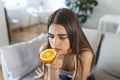 Sick woman trying to sense smell of half fresh orange, has symptoms of Covid-19, corona virus infection - loss of smell and taste Royalty Free Stock Photo