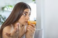 Sick woman trying to sense smell of half fresh orange, has symptoms of Covid-19, corona virus infection - loss of smell and taste Royalty Free Stock Photo