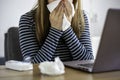 Sick woman working on laptop at home, covering nose and mouth when coughing and sneezing in paper tissue Royalty Free Stock Photo