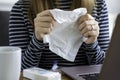 Sick woman working on laptop at home, holding paper tissue to cover nose and mouth to cough or sneeze Royalty Free Stock Photo