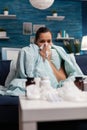 Sick woman wrapped in blanket at home with virus infection