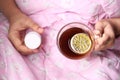 sick women holding lemon tea and pill container