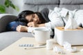 Sick young Asian woman feel cold and has a high fever sleeping on sofa in living room at home. Health problem, winter cold and flu Royalty Free Stock Photo