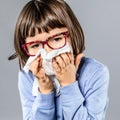 Sick young girl with eyeglasses blowing nose against cold Royalty Free Stock Photo