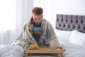 Sick young man eating soup to cure flu in bed Royalty Free Stock Photo