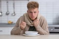 Sick young man eating soup to cure flu at table Royalty Free Stock Photo