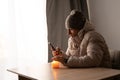 Sick young man feel cold wearing at warm clothes watching movie on smartphone, annoyed guy shiver freezing warming at Royalty Free Stock Photo