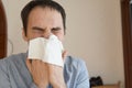 Sick young man suffering from flu at home. a young man sneezes into a rag that would not spread germs. Home quarantine for Royalty Free Stock Photo