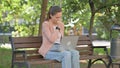 Sick Young Woman Coughing while Using Laptop in Park Royalty Free Stock Photo