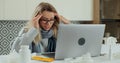 Sick young woman in eyeglasses sit at office homa desk rubs temple, closed eyes while getting sick and taking cure at Royalty Free Stock Photo