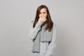 Sick young woman in gray sweater, scarf having runny nose, holding hand on nose on grey wall background Royalty Free Stock Photo