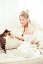 Sick young woman playing with her cat on a sofa Royalty Free Stock Photo