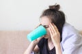 Sick young woman sits at home with a severe headache and drinks pills with water