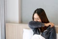 Sickness Asian woman sneezing into her arm in bed room after wake up. Female illness from colds or flu. Allergy or health problem Royalty Free Stock Photo