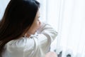 Sickness Asian woman sneezing into her elbow in bed room after wake up. Female illness from colds or flu. Allergy or health proble Royalty Free Stock Photo