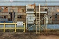 Side of an abandoned brick factory with yellow railing and ladder