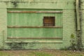 Side of abandoned factory building with bricks painted green Royalty Free Stock Photo