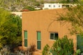 Side of adobe red building with stucco exterior and visible windows in late afternoon sun in neighborhood in hills Royalty Free Stock Photo