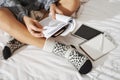 Side angle shot of woman sitting with crossed hands on bed, wearing fancy socks, making notes while studying at home Royalty Free Stock Photo