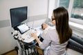 Side angle view of young woman doctor in white coat conducting ultrasound examination of abdomen to a female patient. Royalty Free Stock Photo