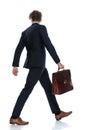 Side back view of businessman holding his briefcase and walking Royalty Free Stock Photo