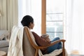 Calm Indian woman relax on comfy armchair with tea cup