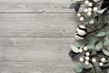 Side border of silver green leaves and white berries over gray wood