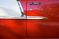 Side of a bright red vintage retro convertible car with chrome details and moldings