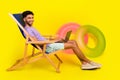 Side cadre of man lying sunbed chair copywriter comfortable freelancer job on beach near rubber rings over