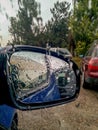 Side car mirror in the rain. Double reflection of a house with an orange roof. Drops of water on the glass.  Close-up Royalty Free Stock Photo