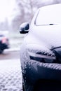 The side of a car starting to get snowed under during a blizzard. The snow already covers the windshield of the vehicle making it