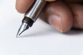 Side close up shot of a fountain pen nib held by fingers and writing on white paper Royalty Free Stock Photo