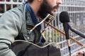 A mixed race man playing guitar in the street