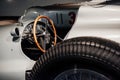 Side, close up view of grey retro sport coupe cabriolet interior and hood: wooden steering wheel, dashboard, mirror