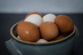 Side close up view of handmade ceramic bowl of fresh organic brown and white eggs on dark and concrete background. Royalty Free Stock Photo